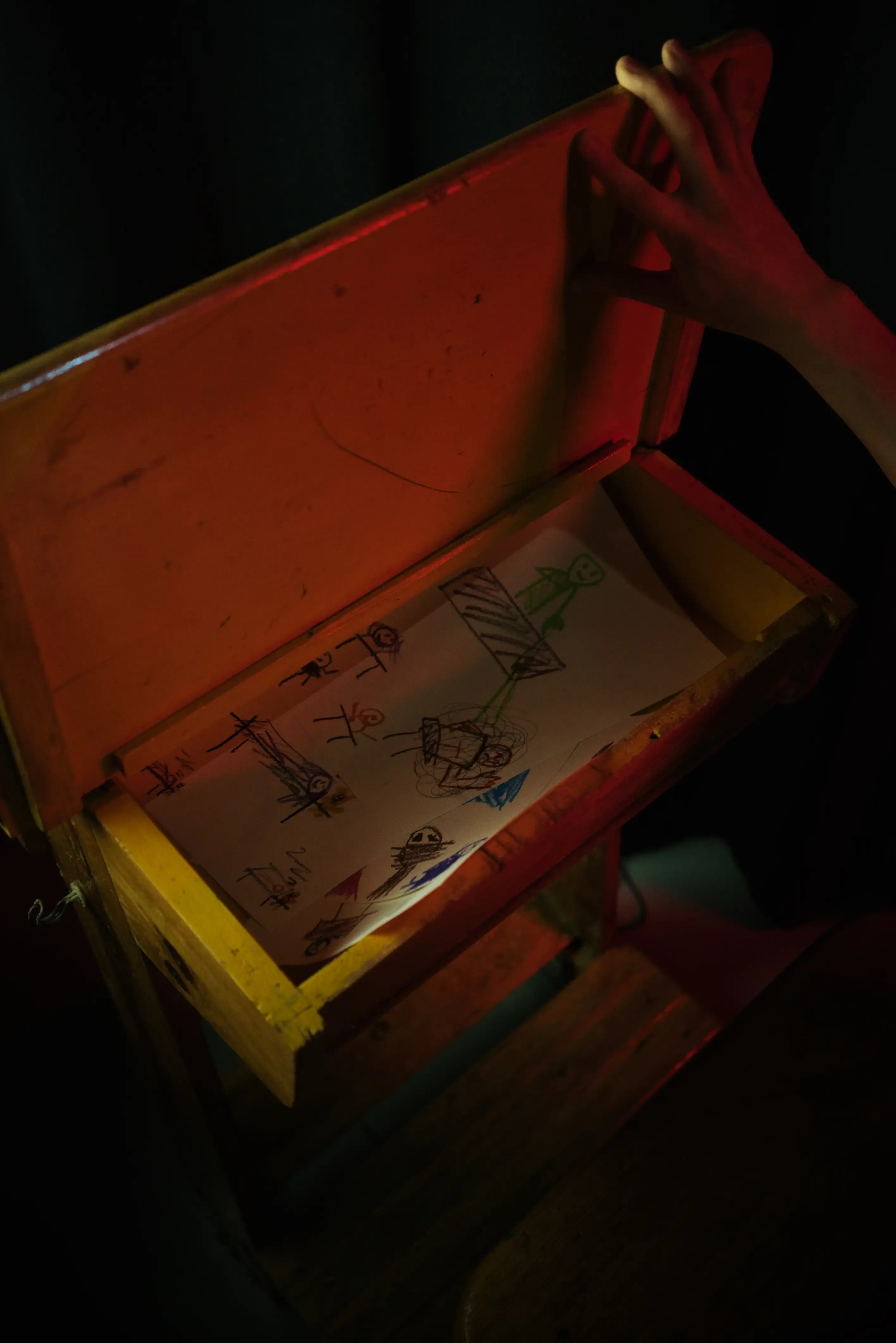 An open school desk with papers and illustrations inside.
